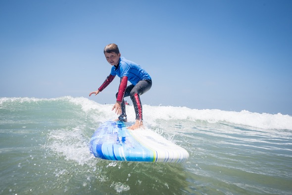 A child riding a surfboard in the water, enjoying the waves and the thrill of surfing in Ocean Beach.